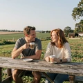 Jake and Sarah, a happy Iowa couple drinking coffee at a picnic table, MileDating trucker dating success story