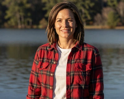 Caroline, a 35-year-old brunette woman in a flannel shirt near a North Georgia lake, featured on MileDating trucker dating Georgia